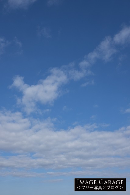 真ん中に雲が密集している青空（横位置）のフリー写真素材（無料）