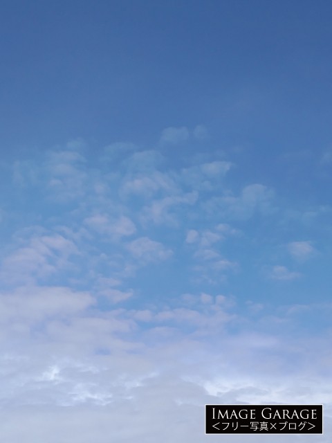 ポツポツした雲がある青空（縦位置）のフリー写真素材
