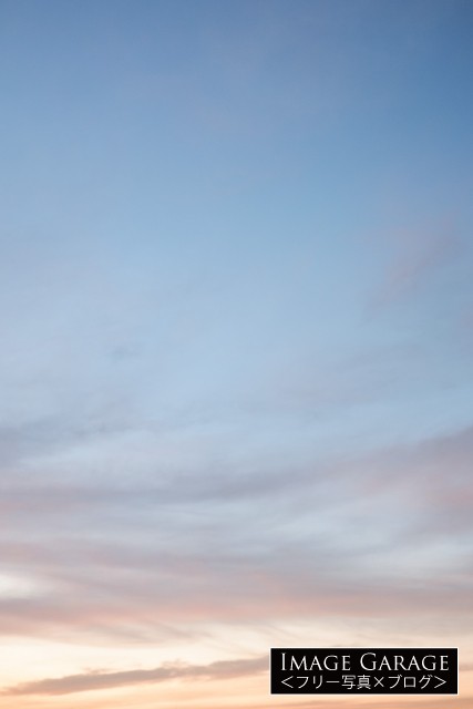 うっすらオレンジがかった青空（縦位置）のフリー写真素材（無料画像）