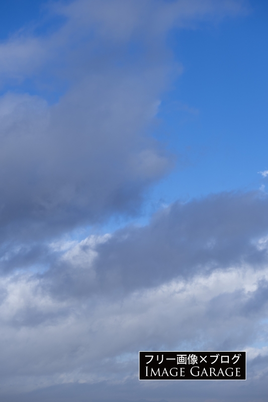 雲多めの青空（縦）のフリー写真素材（無料画像）