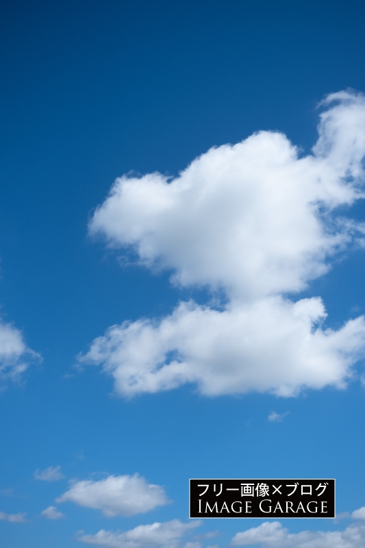 ふわふわの雲が浮かぶ青空（縦）のフリー写真素材（無料画像）