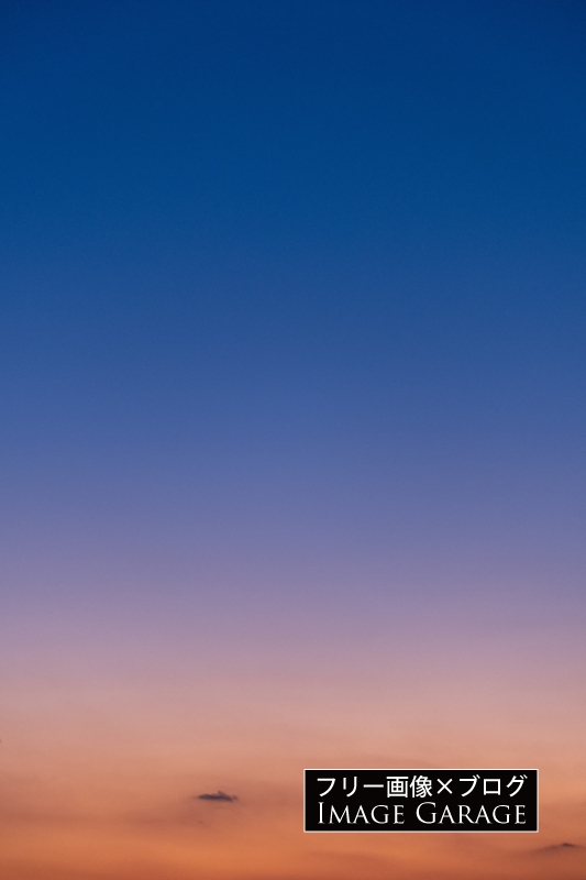 深い青とオレンジの夕焼け空（縦）のフリー写真素材（無料画像）