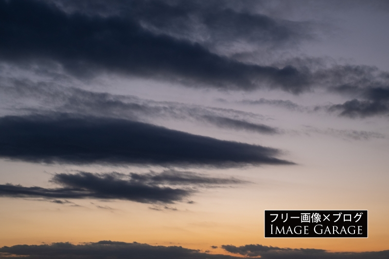 夕焼け空と流れるような黒い雲のフリー写真素材（無料画像）
